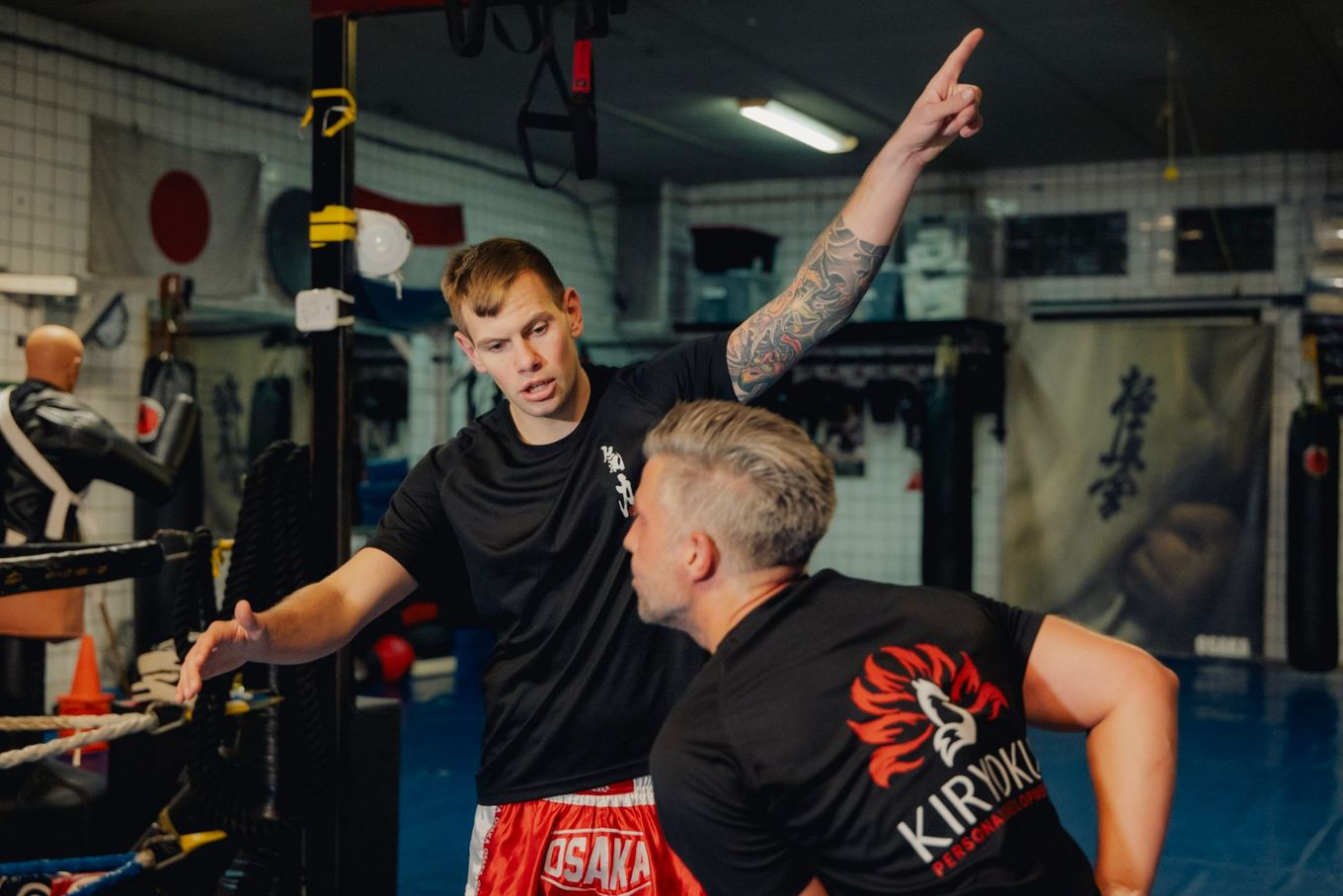Floris legt een klant in een Kiryoku-shirt iets uit in de dojo.