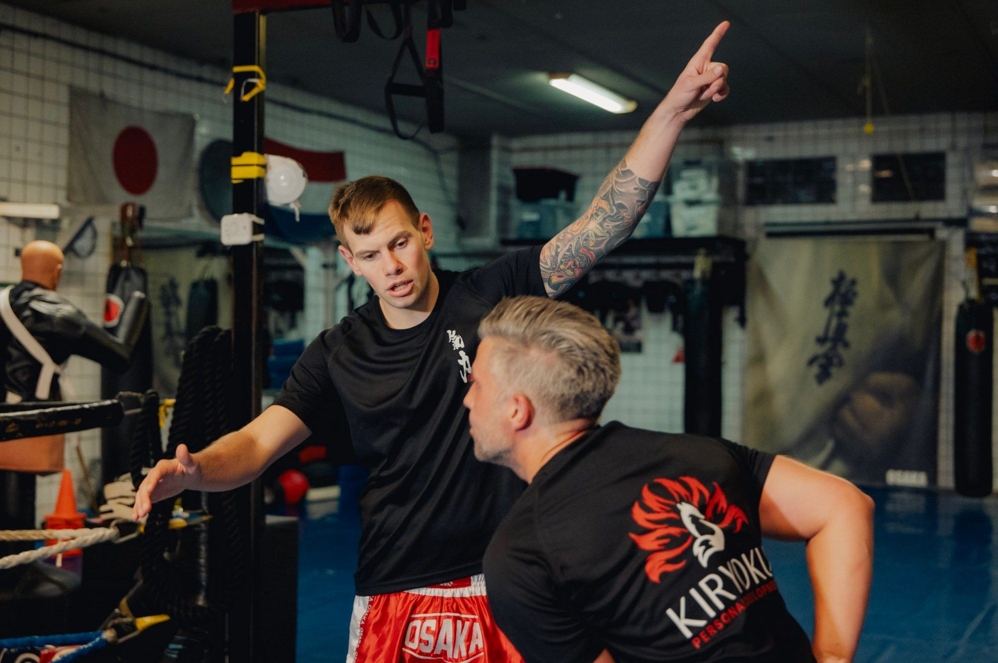 Floris legt een klant in een Kiryoku-shirt iets uit in de dojo.
