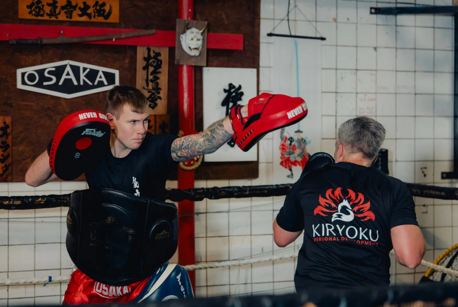 Floris houdt de pads vast voor een klant in een Kiryoku-shirt, in de dojo van Osaka Karate Katwijk.